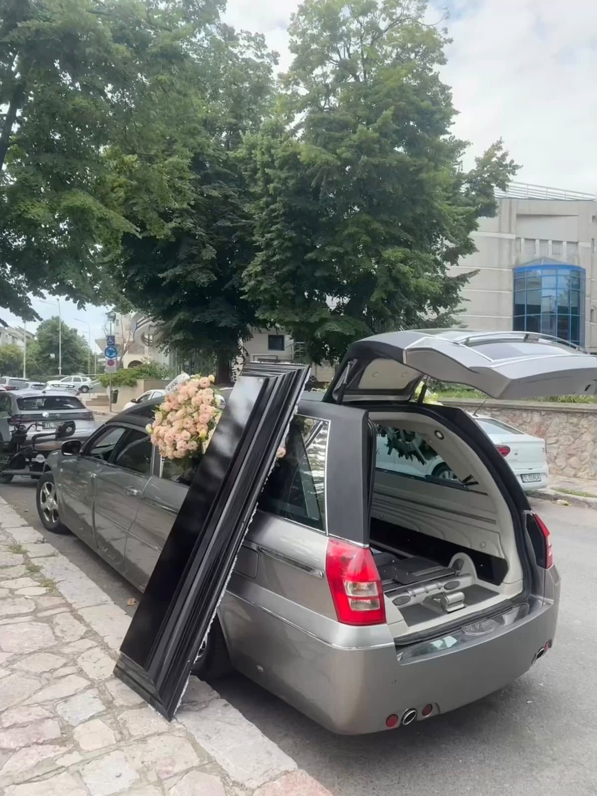 Autospeciala funerară cu ușa deschisă, pregătită pentru ceremonie